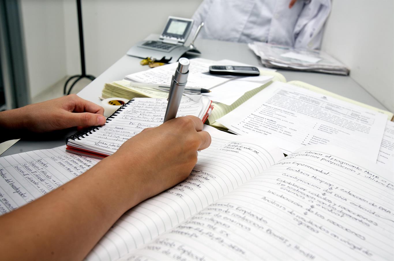 Person Documenting Information On Notebook